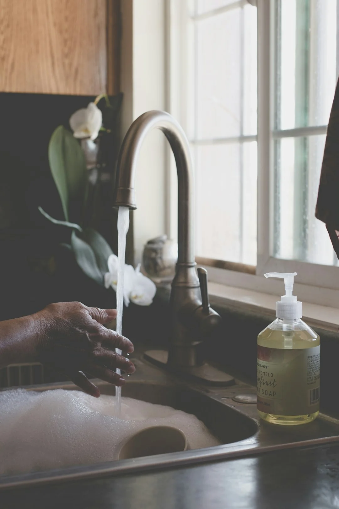 A housekeeper straightening the bed linens in a well-appointed hotel room.